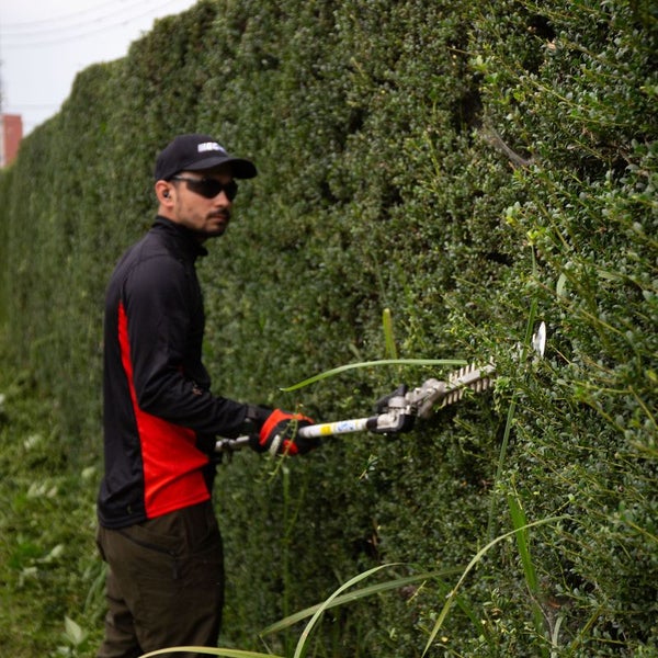 Ein Mann schneidet eine Hecke mit einer Heckenschere.