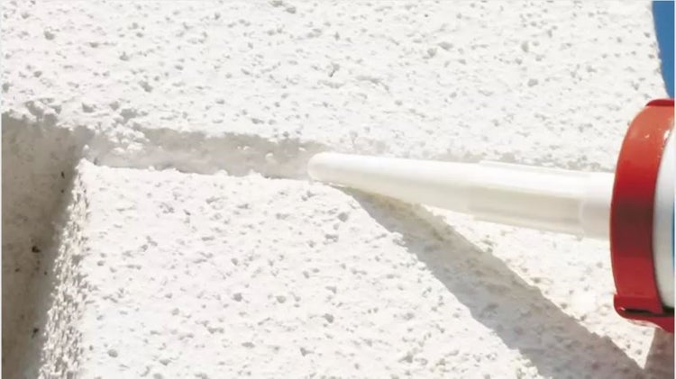 Außenaufnahme einer Fassade, bei der eine Fuge mit Dichtstoff abgedichtet wird.