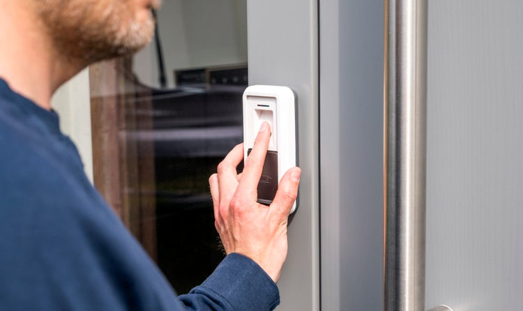 Fingerabdruckscanner von ABUS an einer Haustür, bedient durch eine Person für schlüssellosen Zutritt.