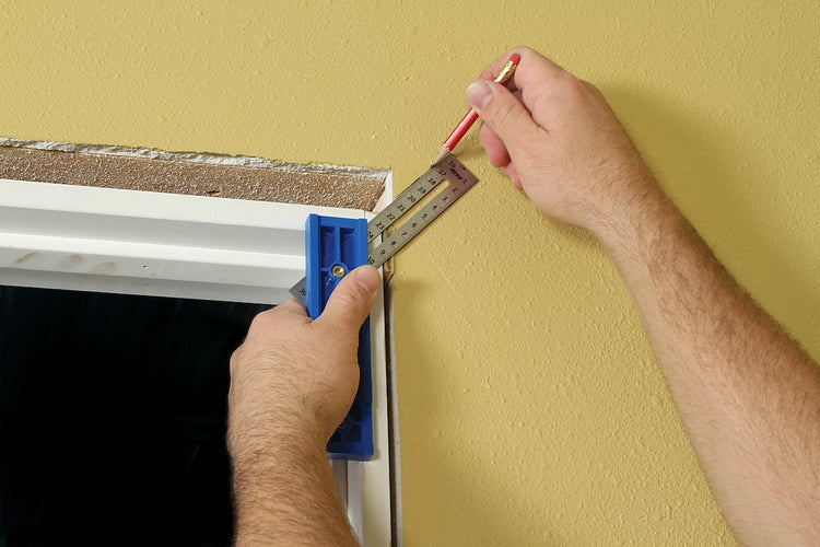 Handwerker verwendet Winkelmesser und Bleistift an einer Fensterleibung.