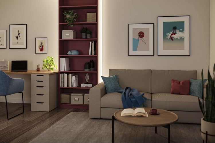 Wohnzimmer mit Sofa, Bücherregal und Schreibtisch.