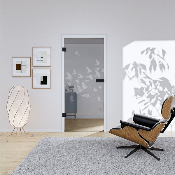 Modernes Wohnzimmer mit einer Ganzglastür mit Vogelmuster, schwarzen Beschlägen, einem Loungesessel, einer Stehleuchte und einem grauen Teppich.