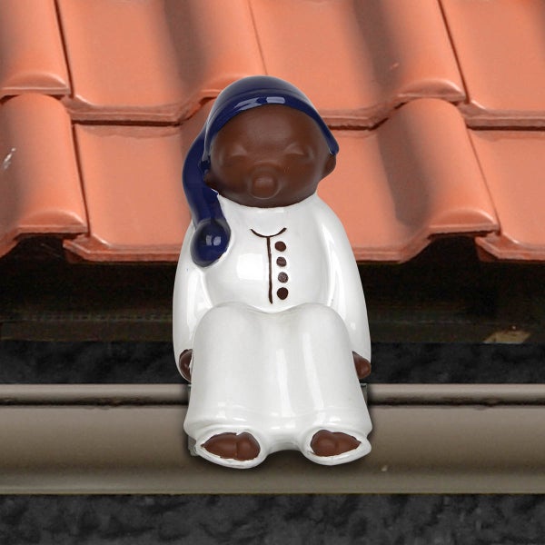 Dekorative Dachrinnenfigur als sitzendes Männchen mit Schlafmütze auf einem Hausdach.