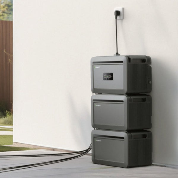 Modularer Batteriespeicher mit drei gestapelten Einheiten an einer Wand, angeschlossen an eine Steckdose mit mehreren abgehenden Kabeln.