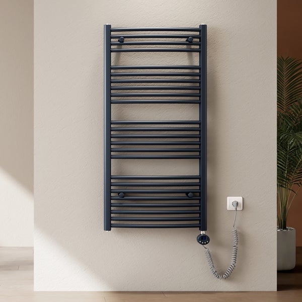 Moderner elektrischer Badheizkörper in Anthrazit an einer strukturierten Wand, inklusive digitalem Thermostat und Spiralkabel in einem hellen Raum.