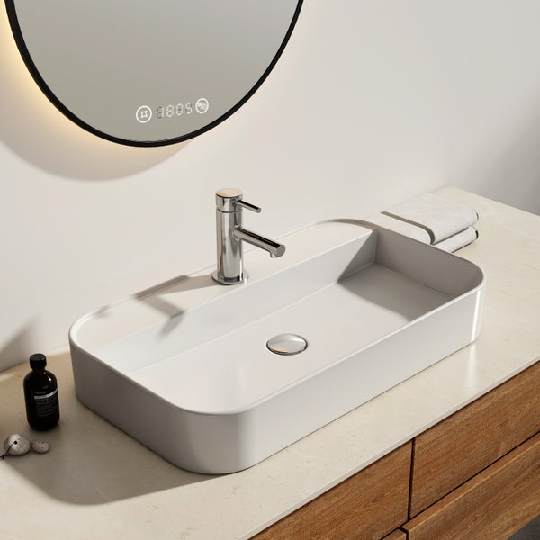 Modernes Badezimmer mit rechteckigem Aufsatzwaschbecken, verchromter Armatur und rundem Spiegel mit digitaler Anzeige auf einem Holzunterschrank.