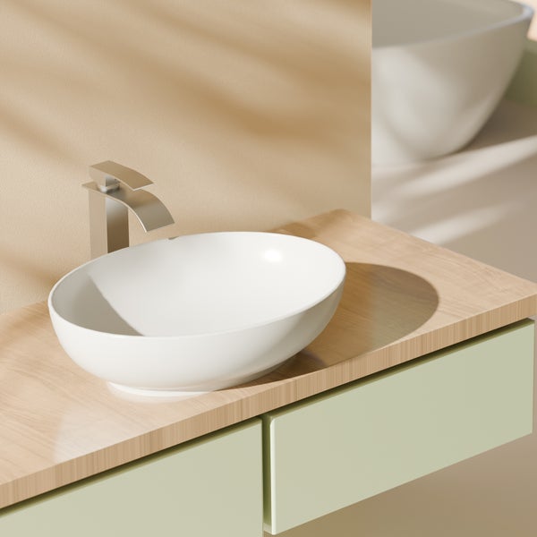 Modernes Badezimmer mit ovalem Keramik-Aufsatzwaschbecken, einer Einhebelarmatur und einer Holz-Waschtischplatte auf einem hellgrünen Unterschrank.