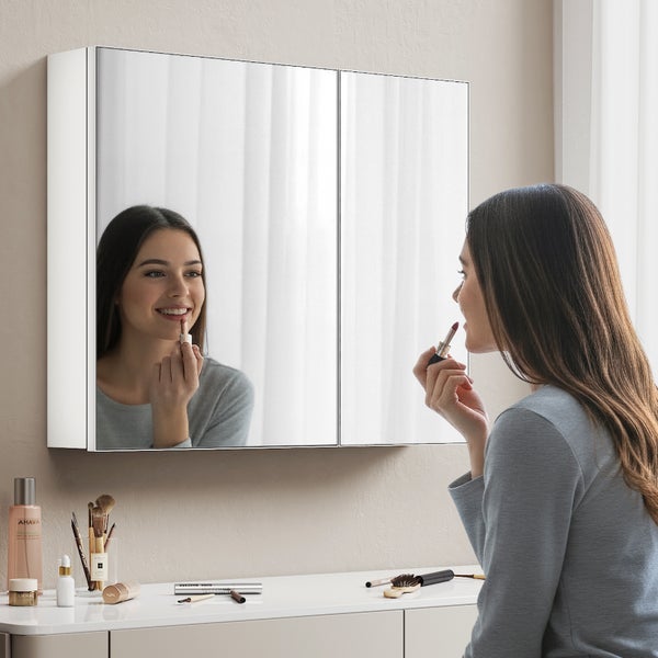 Frau vor einem Spiegelschrank im Badezimmer beim Auftragen von Lippenstift