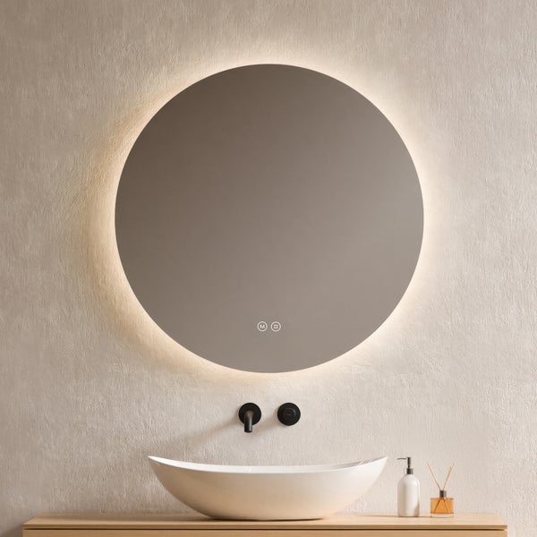 Runder LED-Badspiegel mit Hintergrundbeleuchtung und Touch-Sensoren über einem weißen Aufsatzwaschbecken und einer schwarzen Wandarmatur.