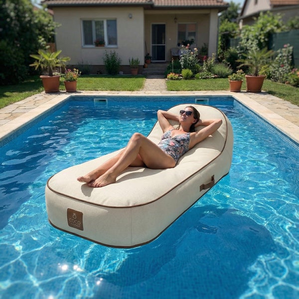 Eine Frau entspannt auf einem beigen schwimmenden Pool-Sitzsack von COCO LOUNGE in einem hellen Gartenpool.