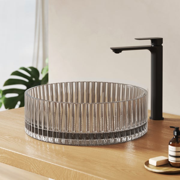 Klares Glaswaschbecken mit geripptem Design und schwarzer Armatur auf einem Holztisch