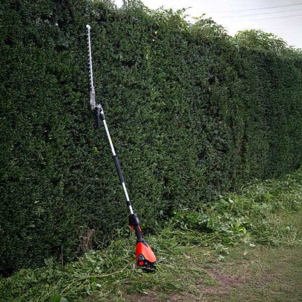 Akku-Teleskop-Heckenschere vor einer grünen Hecke