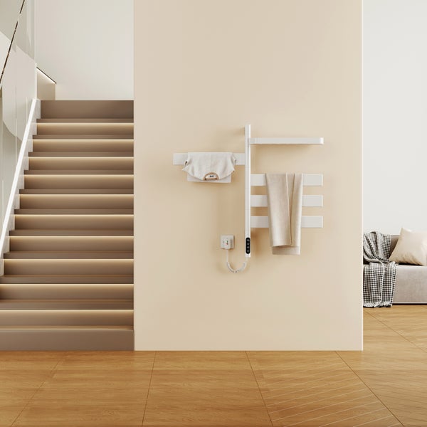 Elektrischer Handtuchheizkörper an einer hellen Wand in einem modernen Wohnraum mit beleuchteter Treppe und Holzboden.