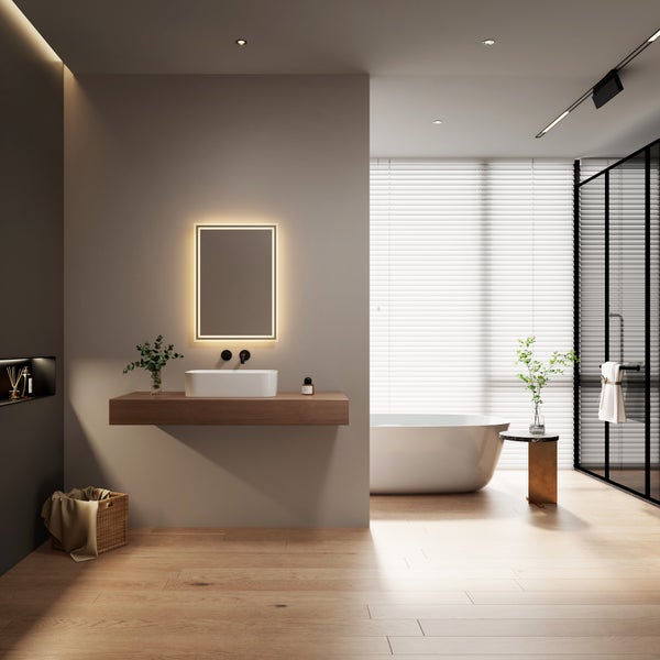 Modernes Badezimmer mit freistehender Badewanne, Waschbecken auf Holzplatte, beleuchtetem Spiegel, Holzfußboden und Jalousien vor dem Fenster.