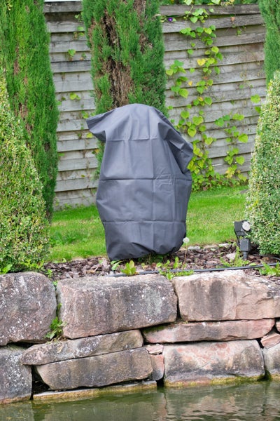 Eine wetterfeste Abdeckhaube schützt einen Gegenstand im Garten vor Witterungseinflüssen.