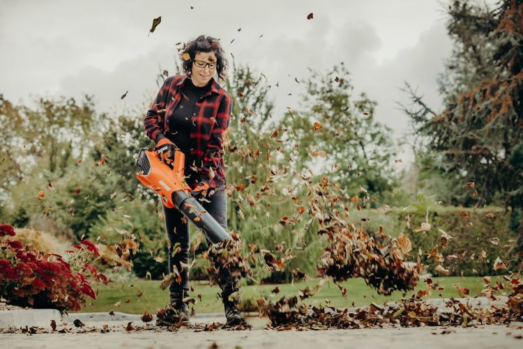 Frau benutzt einen Laubsauger zur Gartenarbeit
