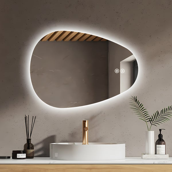Organisch geformter Badezimmerspiegel mit LED Beleuchtung und Touch Funktion montiert über einem Waschtisch mit Aufsatzwaschbecken.