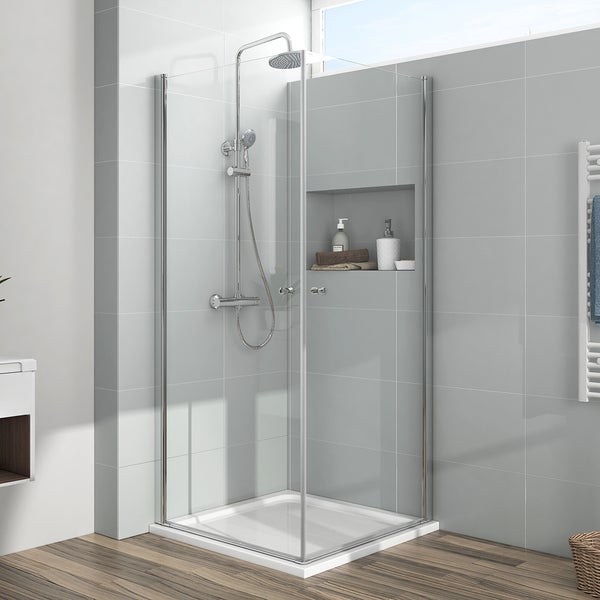 Moderne Eckdusche mit Glaswänden, verchromtem Duschsystem und flacher Duschwanne in einem hellen, gefliesten Badezimmer.