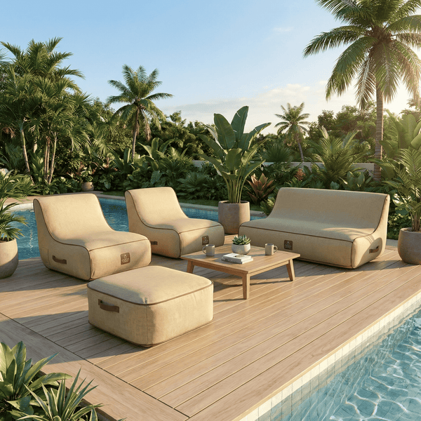 Moderne Gartenlounge mit beigen Polstersesseln, Sofa und Hocker auf einer Holzterrasse am Pool, umgeben von tropischen Pflanzen.