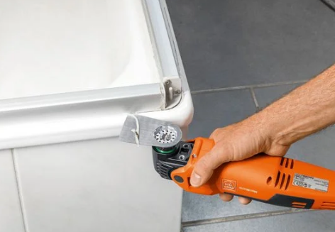 FEIN MultiMaster Multitool mit Schaber beim Entfernen einer Silikonfuge am Rand einer Badewanne.