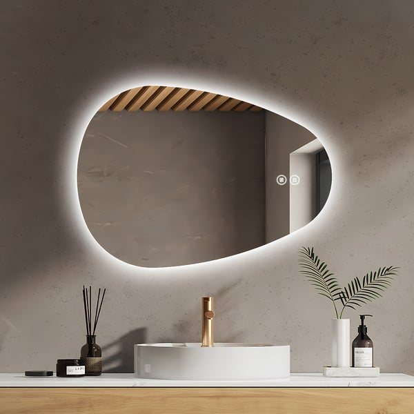 Organisch geformter Badezimmerspiegel mit LED Beleuchtung und Touch Funktion über einem runden Aufsatzwaschbecken mit goldener Armatur im Bad.