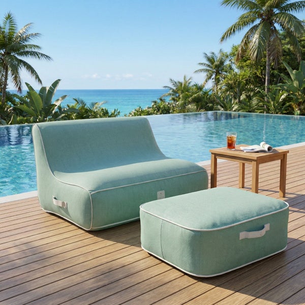 Helles, modernes Outdoor-Loungesofa und Hocker aus mintgrünem Stoff auf einer geräumigen Holzterrasse neben einem Pool mit Meerblick.