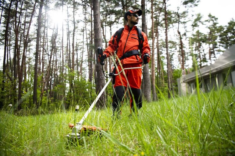 Mann mit einem Rasentrimmer im Garten, der das Gras schneidet