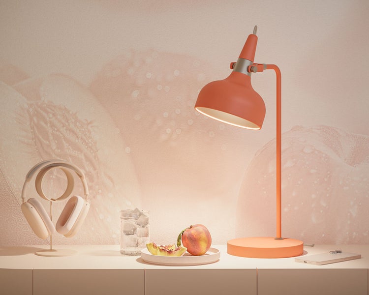 Szene mit Schreibtischlampe, Kopfhörern, Glas mit Eis, Pfirsich und Smartphone auf einem Tisch