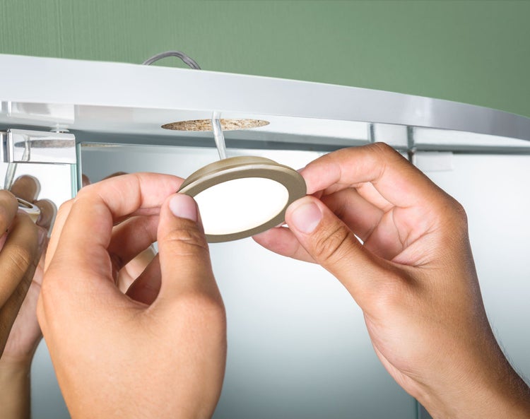 Installation einer runden LED-Einbauleuchte in einem Badezimmerschrank