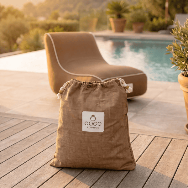 Stoffbeutel mit Coco Lounge Logo auf einer Holzterrasse mit einer Sonnenliege und einem Pool im Hintergrund.