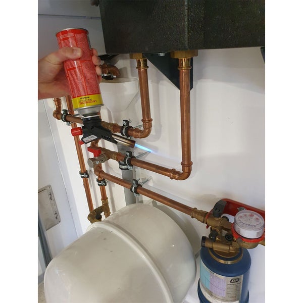 Handwerker lötet ein Kupferrohr an einer Hauswasserinstallation mit einem Rothenberger Gasbrenner