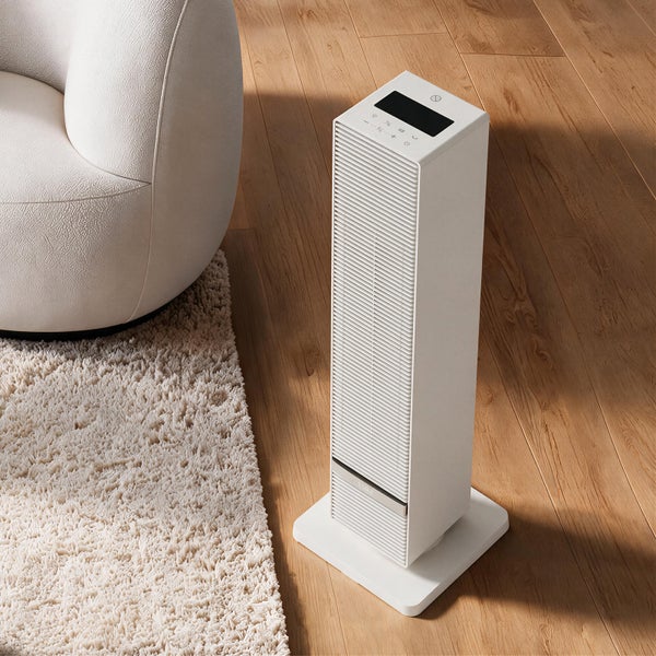 Elektrischer Turmheizlüfter von EMKE mit Digitalanzeige, platziert auf einem Holzboden neben einem Sessel und einem Teppich.
