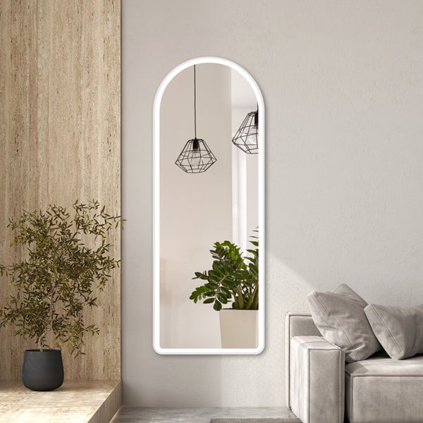 Bogenförmiger Ganzkörperspiegel mit LED-Beleuchtung in einem hellen, modernen Wohnzimmer neben einem Sofa und einer Holzoptik-Wand.