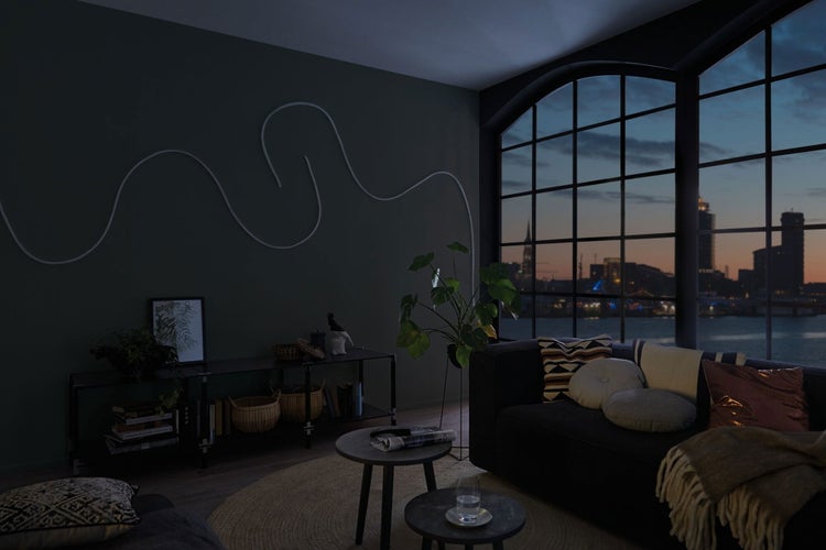 Wohnzimmer mit Sofa, Tisch und Dekorationsartikeln vor einem Fenster mit Stadtblick