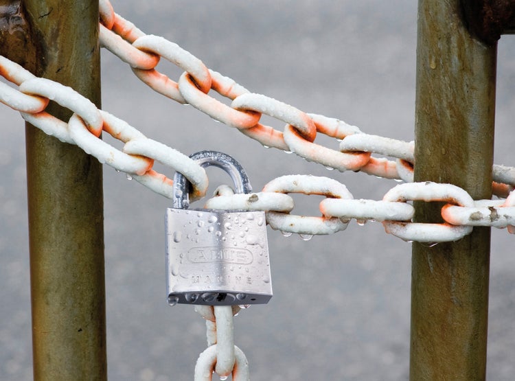 ABUS Vorhängeschloss Marine aus Edelstahl sichert eine Kette im Außenbereich bei Regen.