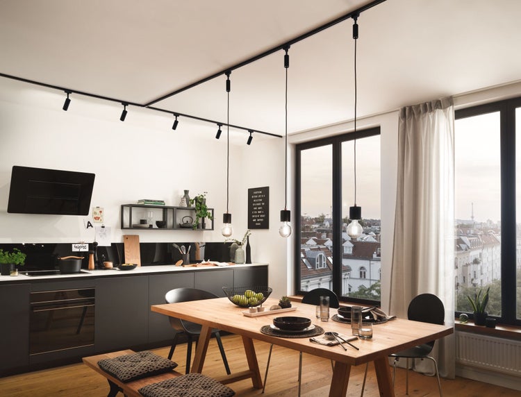 Helle Küche mit Esstisch und schwarzem Schienensystem mit Strahlern und Pendelleuchten