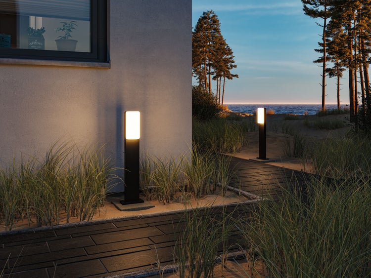 Beleuchtete Außenleuchten säumen einen Gehweg zum Strand.