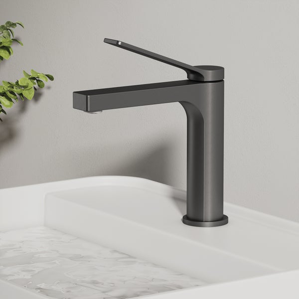 Einzelner, dunkler Wasserhahn auf einem weißen Waschbecken