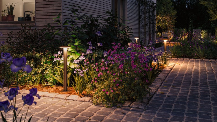 Gartenlandschaft mit Blumen und Wegeleuchten