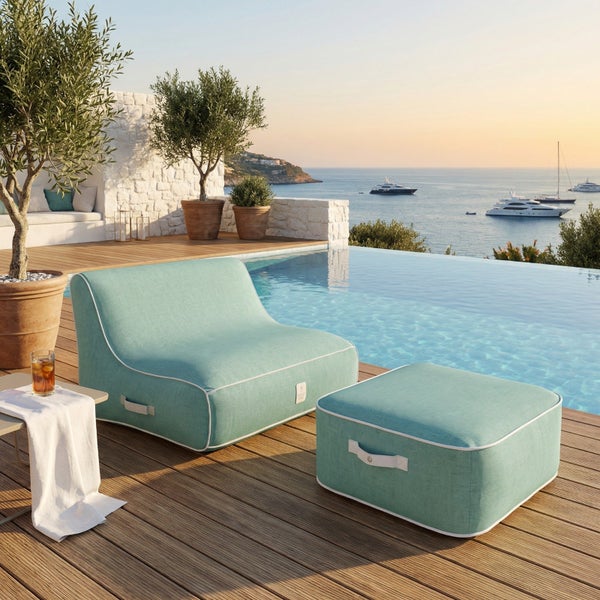 Moderner türkisfarbener Outdoor-Loungesessel mit passendem Hocker auf einer Holzterrasse an einem Infinity-Pool mit Meerblick.