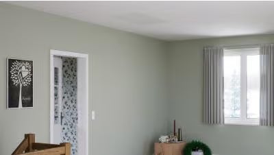 Ein hell eingerichtetes Wohnzimmer mit gestrichenen Wänden, einem Fenster mit Vorhängen, einer Tür und einem Wandbild in einem modernen Stil.