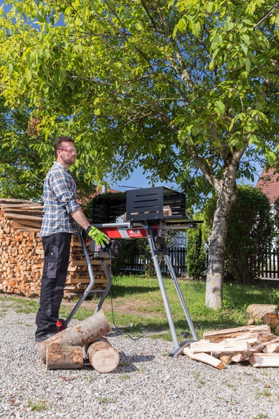 Ein Mann bedient einen liegenden AL-KO Holzspalter im Garten, um Brennholz zu spalten.
