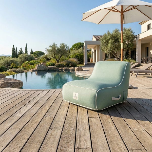 Moderner grüner Outdoor-Sitzsack mit Roolf Living Logo auf einer Holzterrasse am Pool im hellen Garten mit Sonnenschirm.
