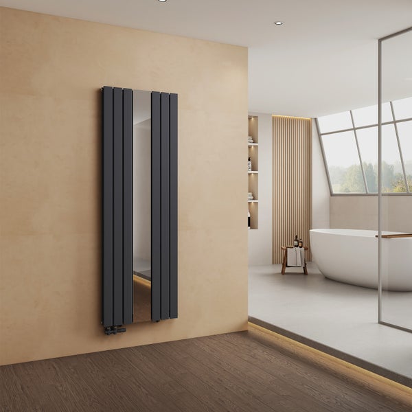 Vertikaler Design-Heizkörper in Anthrazit mit integriertem Spiegel in einem hellen, modernen Badezimmer mit freistehender Badewanne.