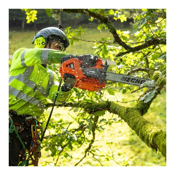 Ein Mann, der mit einer Echo Motorsäge einen Baum beschneidet, wobei Holzspäne in der Luft fliegen.