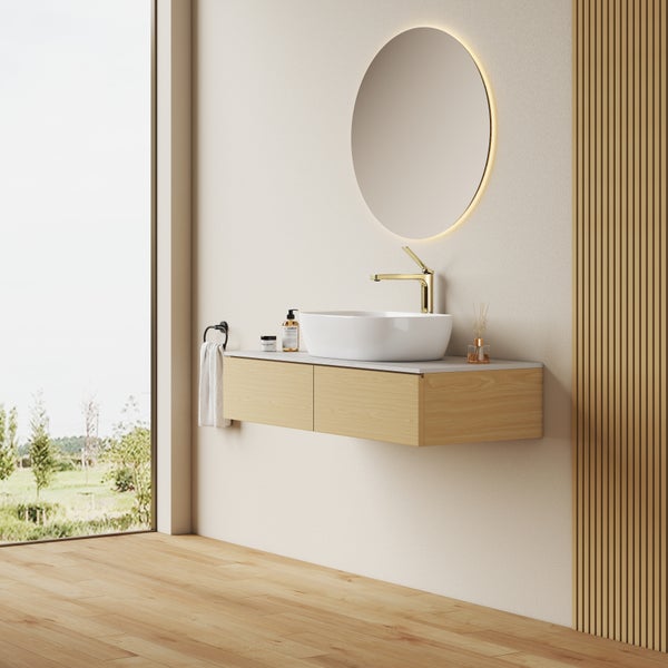 Modernes Badezimmer mit Waschtisch, Aufsatzwaschbecken, goldener Armatur, rundem LED Spiegel und Holzoptik Möbeln in heller, ruhiger Atmosphäre.