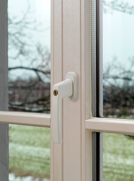 Abschließbarer Fenstergriff in Weiß, montiert an einem weißen Fensterrahmen.