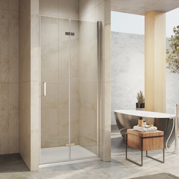 Modernes, helles Badezimmer mit einer Glas-Duschtür mit Metallgriff, einer freistehenden Badewanne und hellen Fliesen in Natursteinoptik.