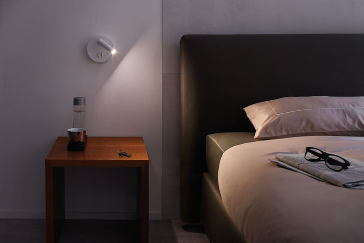 Schlafzimmer mit Nachttisch, Bett und Wandleuchte