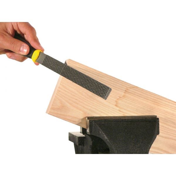 Hand mit einer Holzraspel, die an einem Holzbrett in einem Schraubstock arbeitet